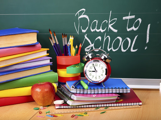 Stack of books, an apple, alarm clock, and the words "back to school!" on a chalkboard